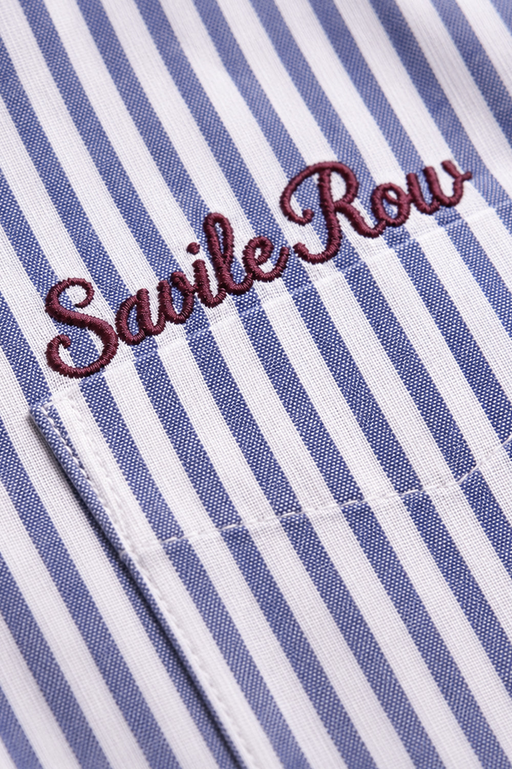 "Savile Row" script embroidery on the chest pocket of the blue Striped Shirt.