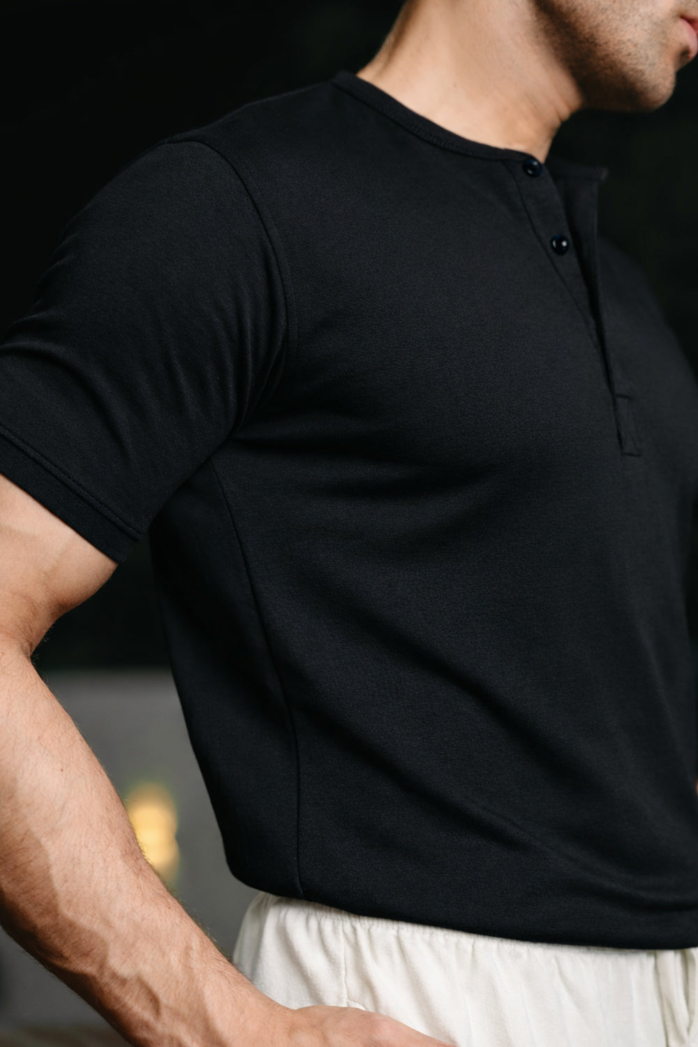 Close-up of man wearing black Henley highlighting fabric texture and fit
