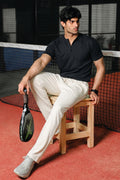 Man wearing black Henley seated on a tennis court bench
