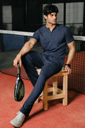 Man wearing navy Henley seated on a tennis court bench

