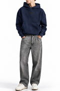 Man wearing the Navy NYC Hoodie with grey jeans, front view