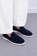 Man wearing navy suede penny loafers with white trousers