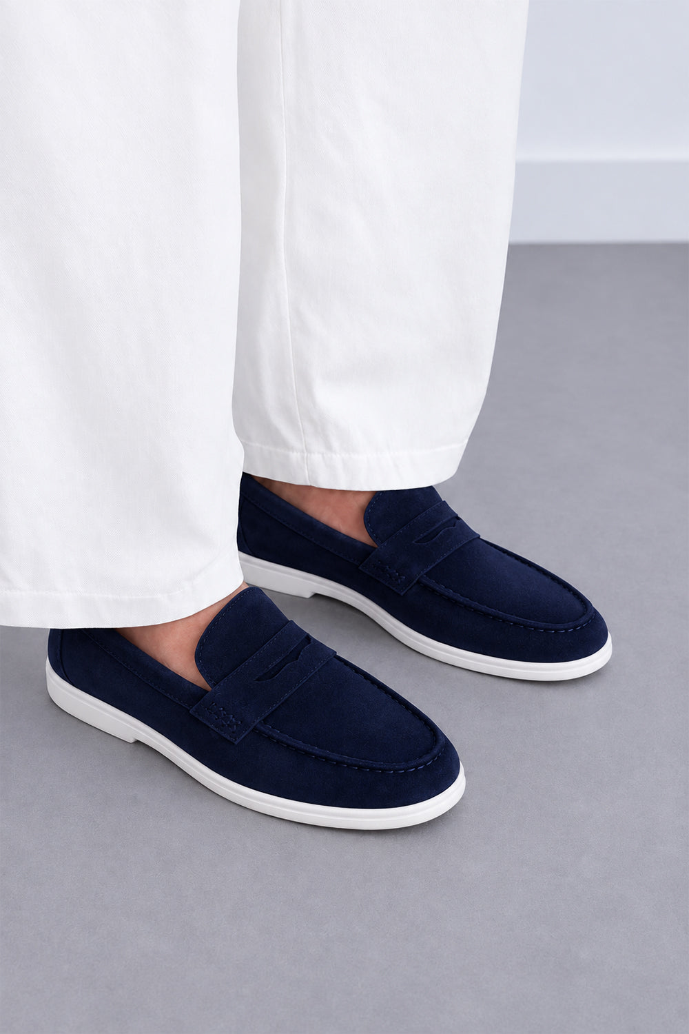 Man wearing navy suede penny loafers with white trousers