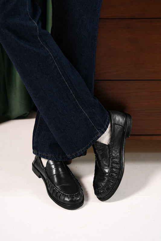 Man wearing the Black Ruched Penny Loafers with navy trousers, angled view