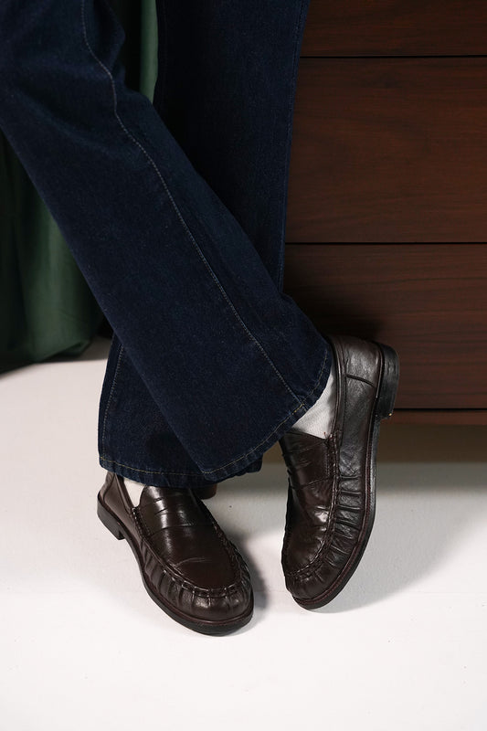 Man wearing the Brown Ruched Penny Loafers with navy trousers, angled view